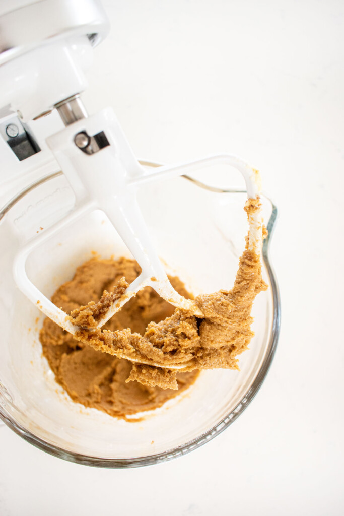 creamed butter and sugar in a glass mixing bowl on a white marble counter.