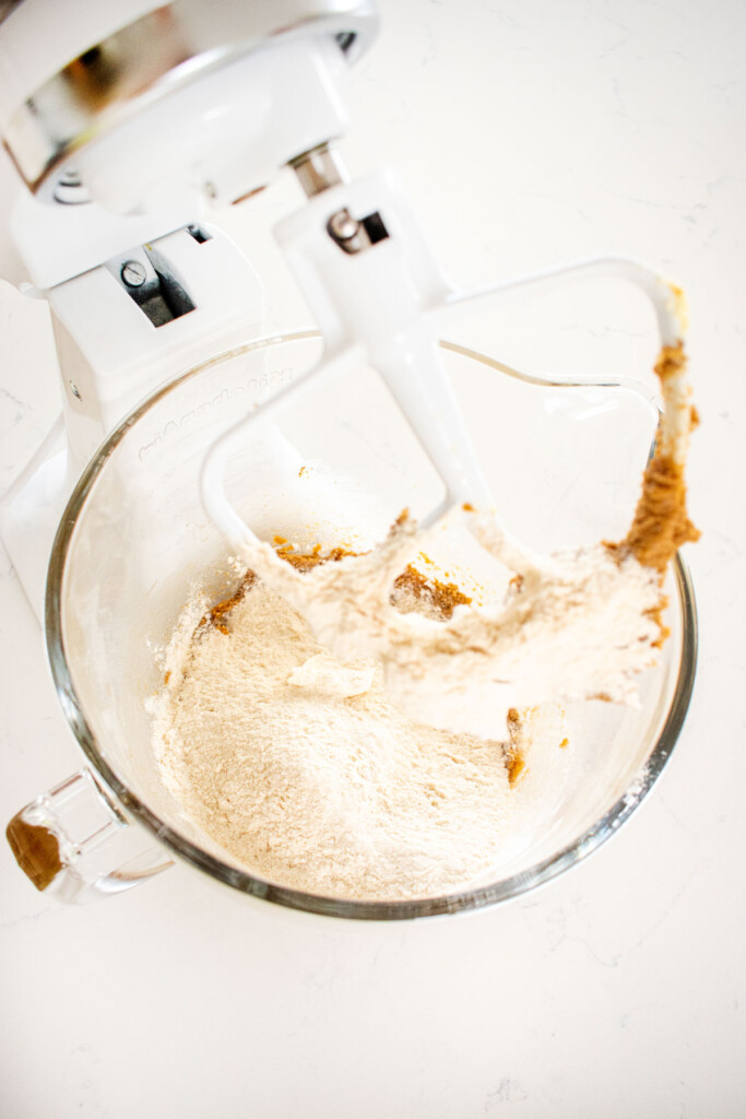 ingredients for cream cheese chocolate chip cookies in a glass mixing bowl on a white marble counter.