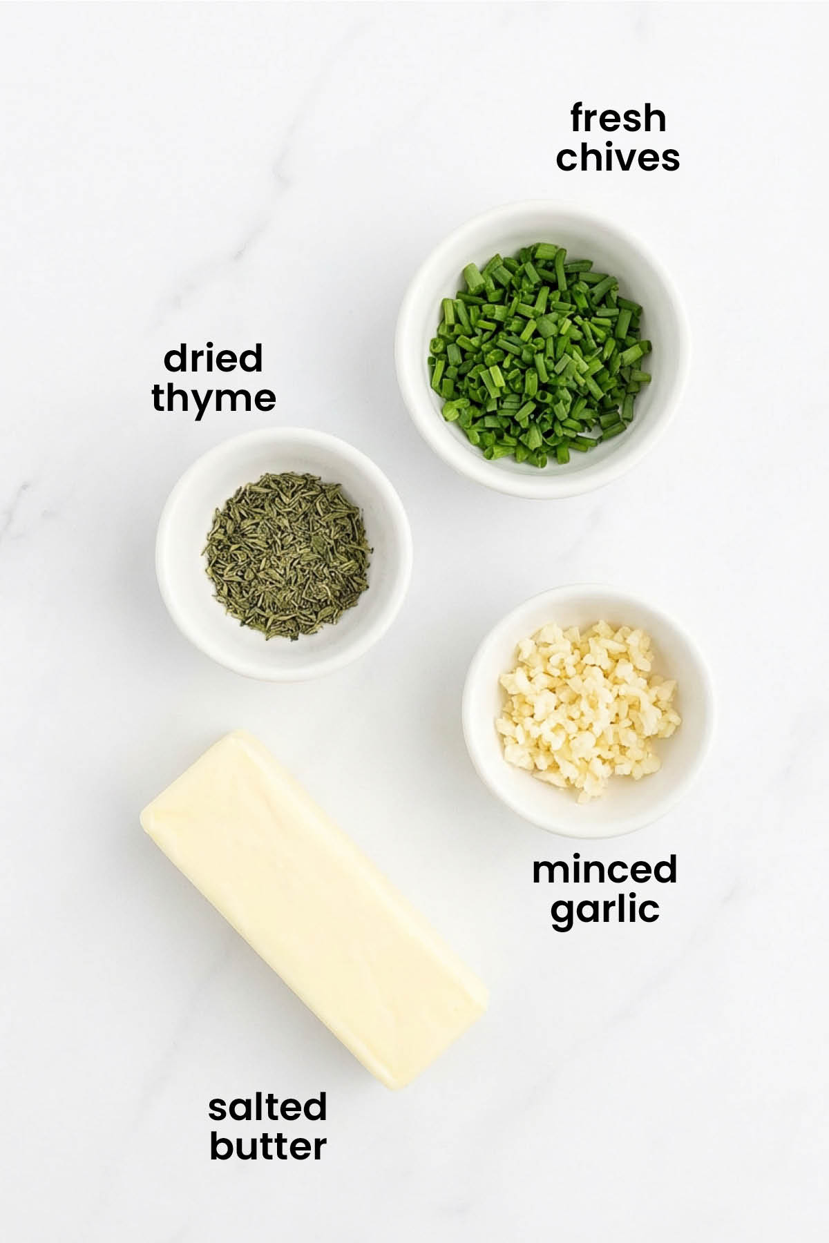 individual ingredients for garlic herb butter laid out against a white background.