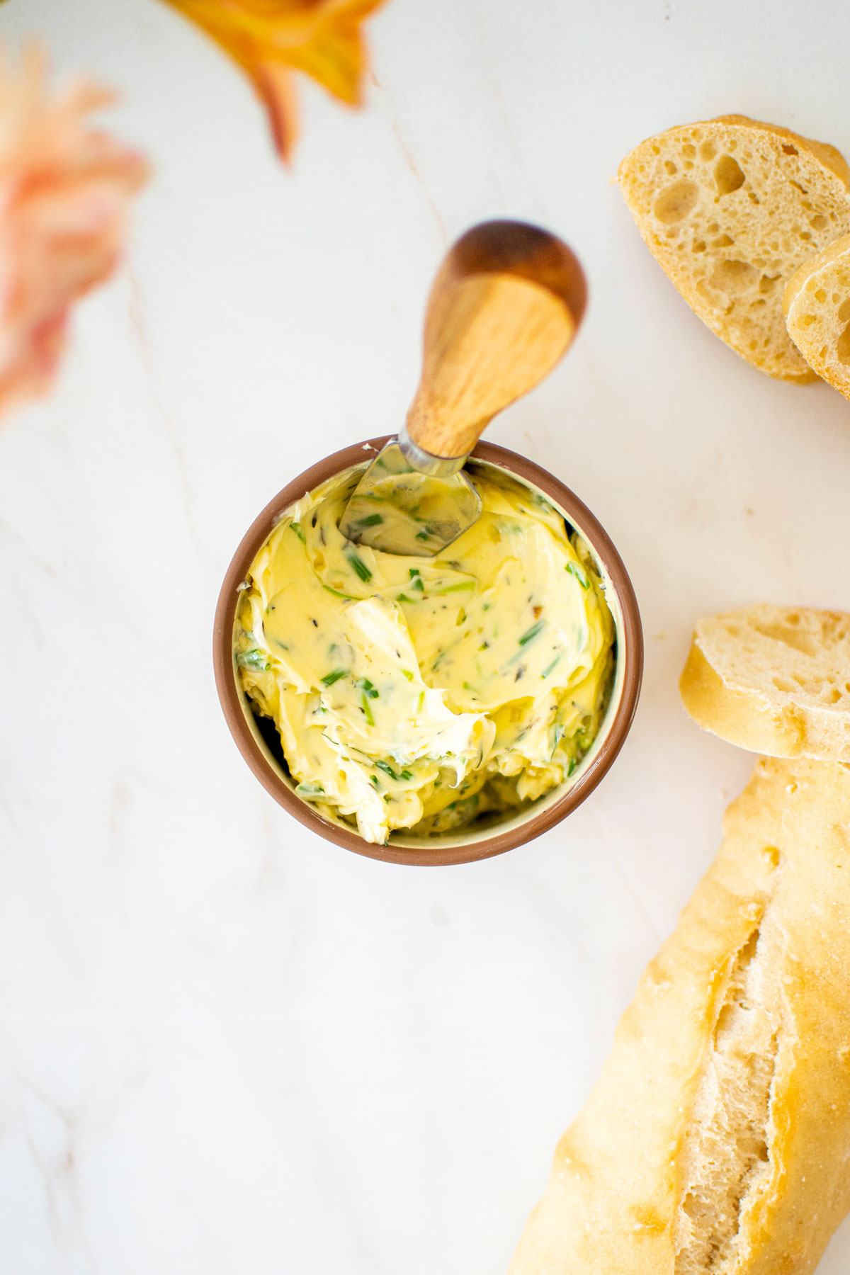 easy garlic herb butter in a small bowl with a wooden handled tiny knife and fresh bread on a marble table.
