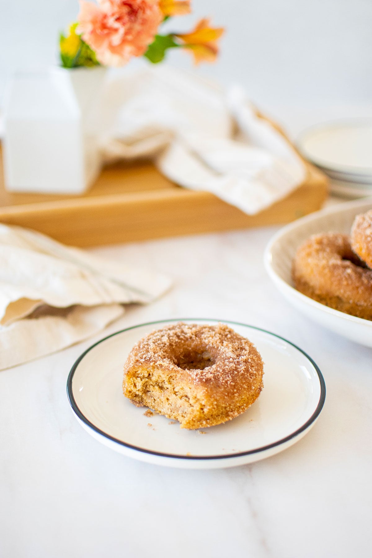 snickerdoodle banana baked donut with a bite taken out on a plate.