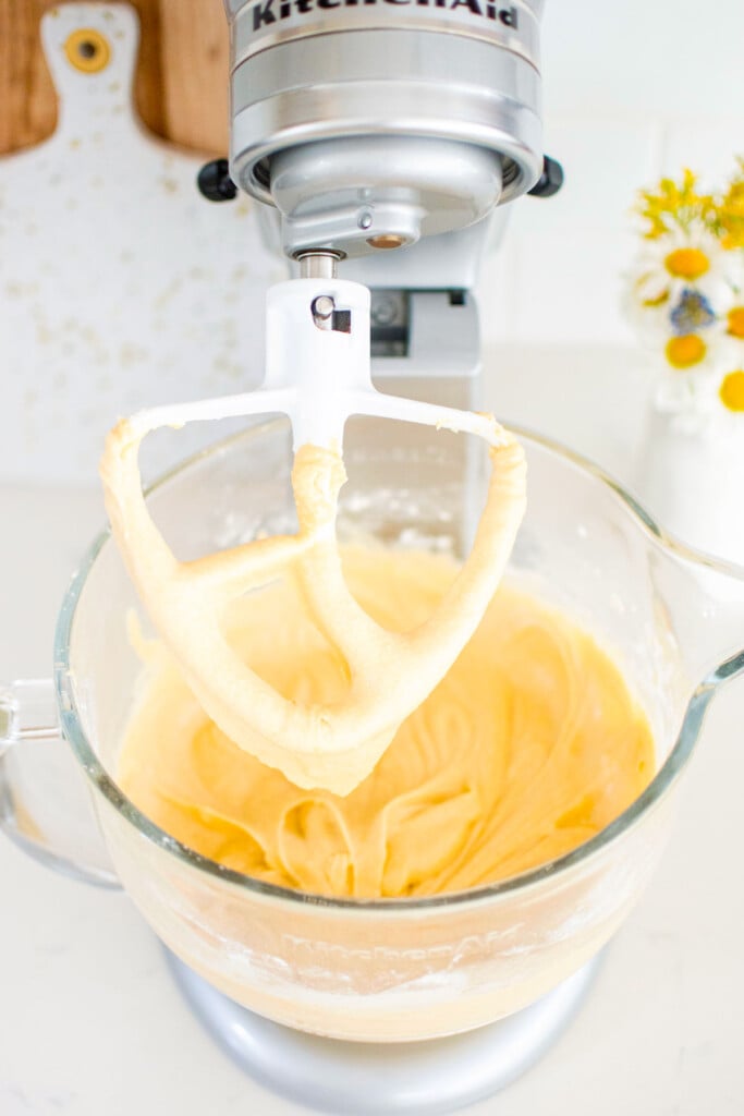 sourdough lavender lemon cake batter in a glass stand mixing bowl on a white marble counter.