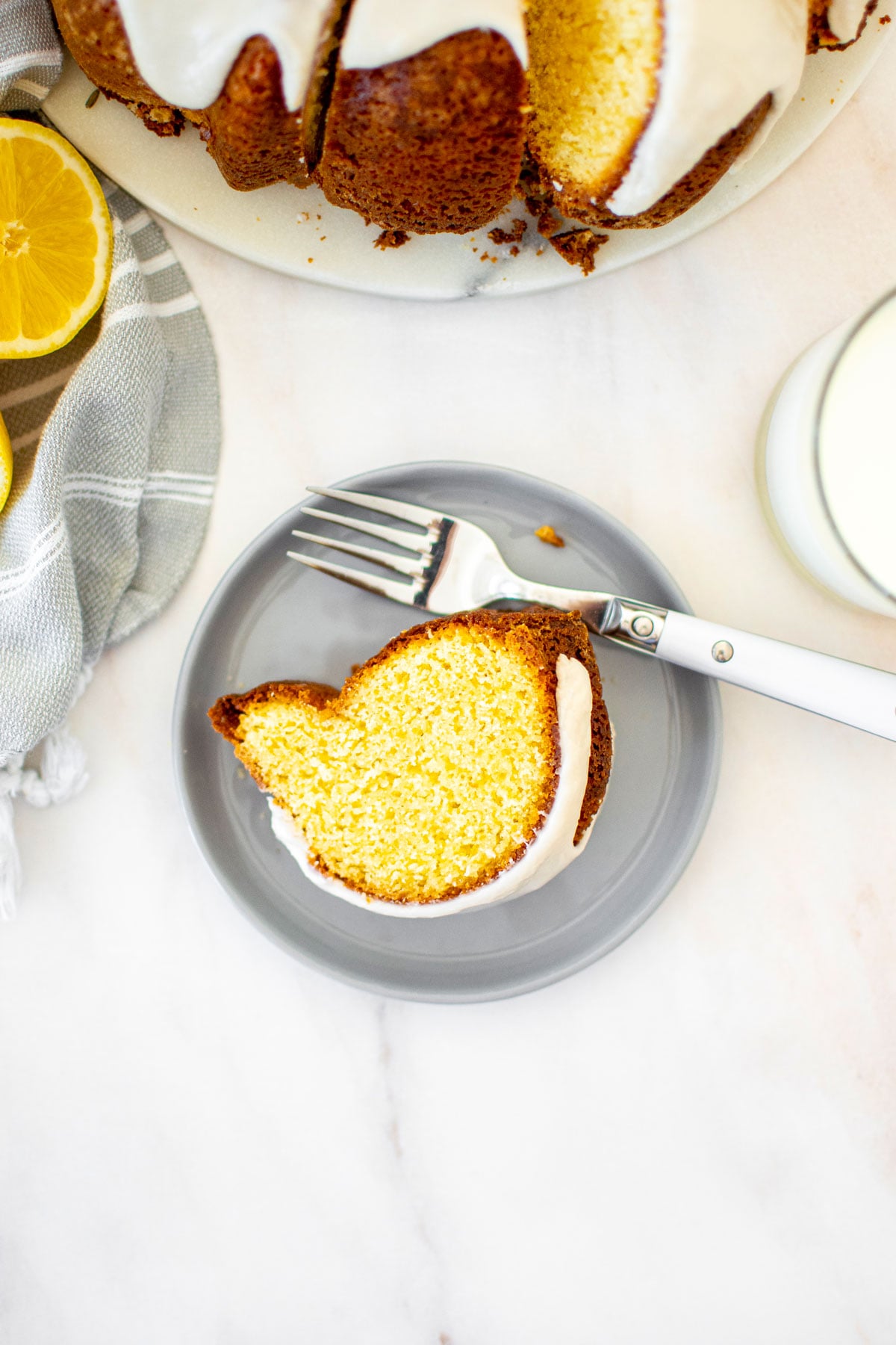 sourdough lavender lemon bundt cake slice on a cake plate with a fork on a marble table.