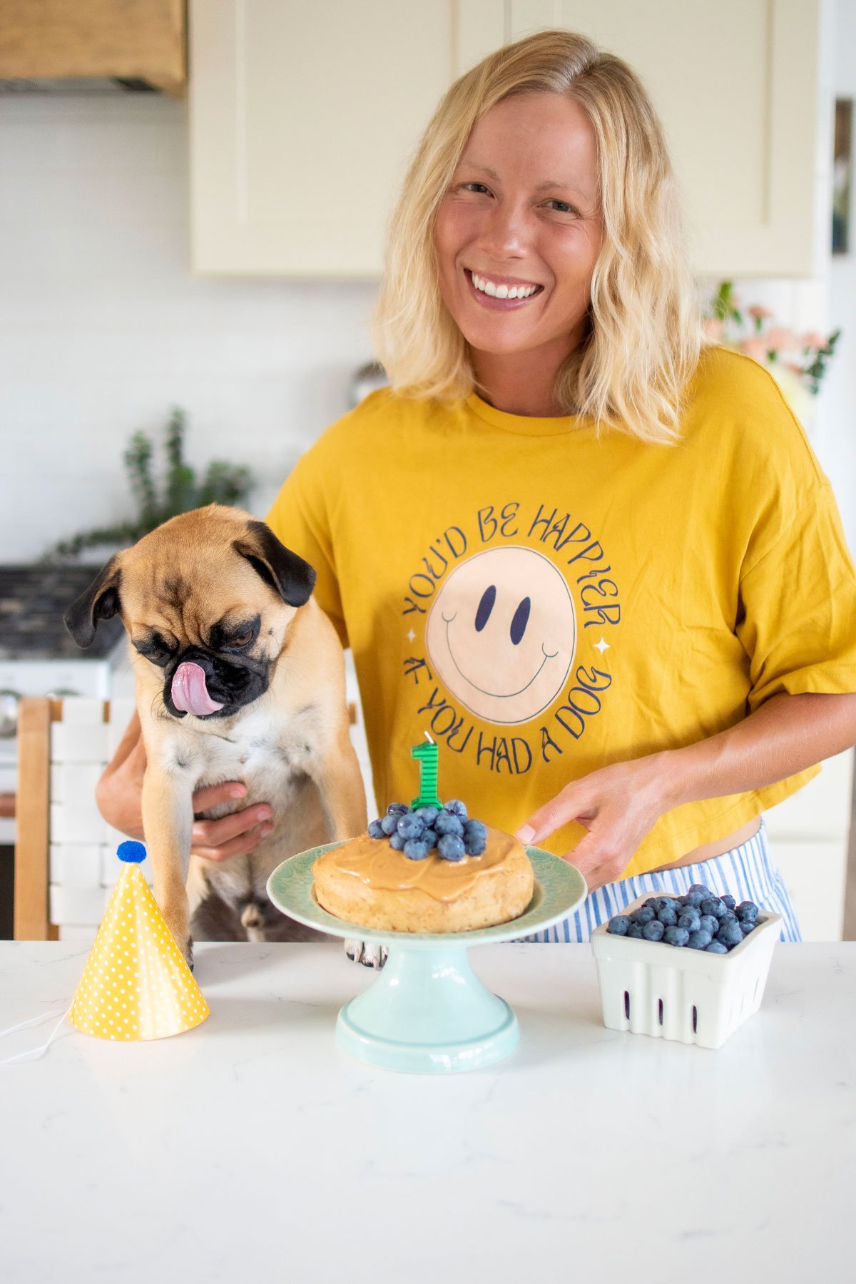 blueberry peanut butter dog cake being enjoyed in kitchen by a pug