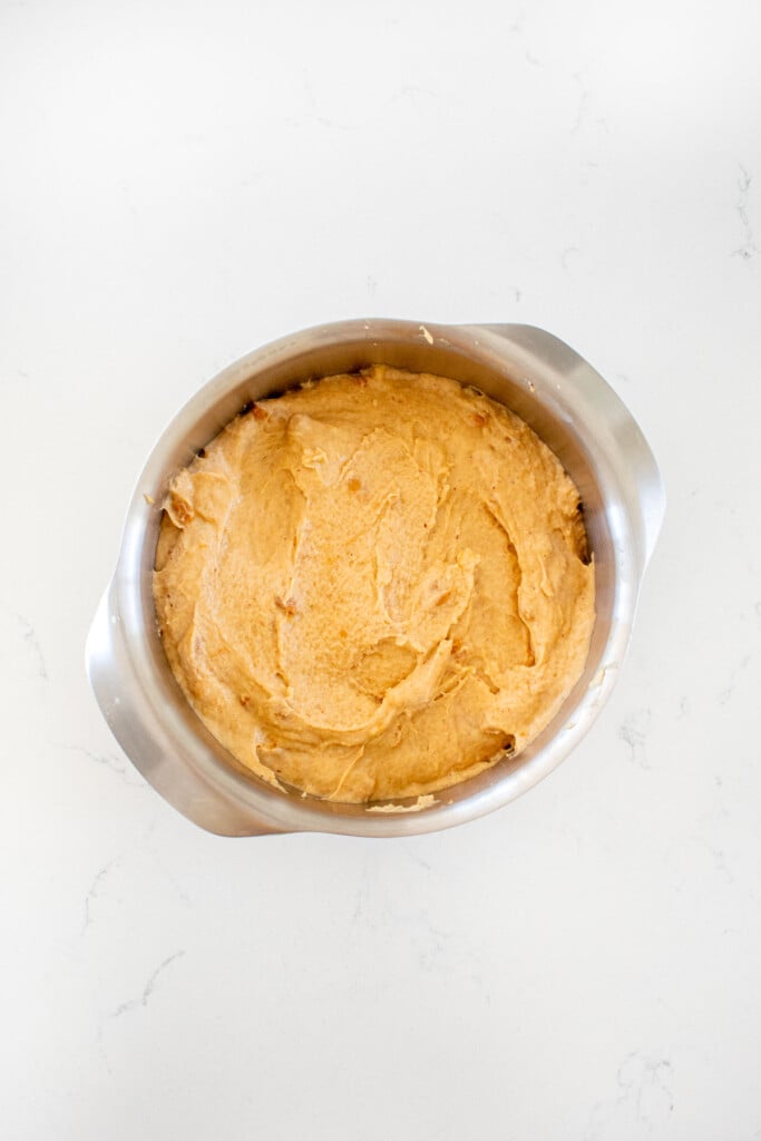 blueberry peanut butter dog cake batter in cake pan on a white marble countertop.