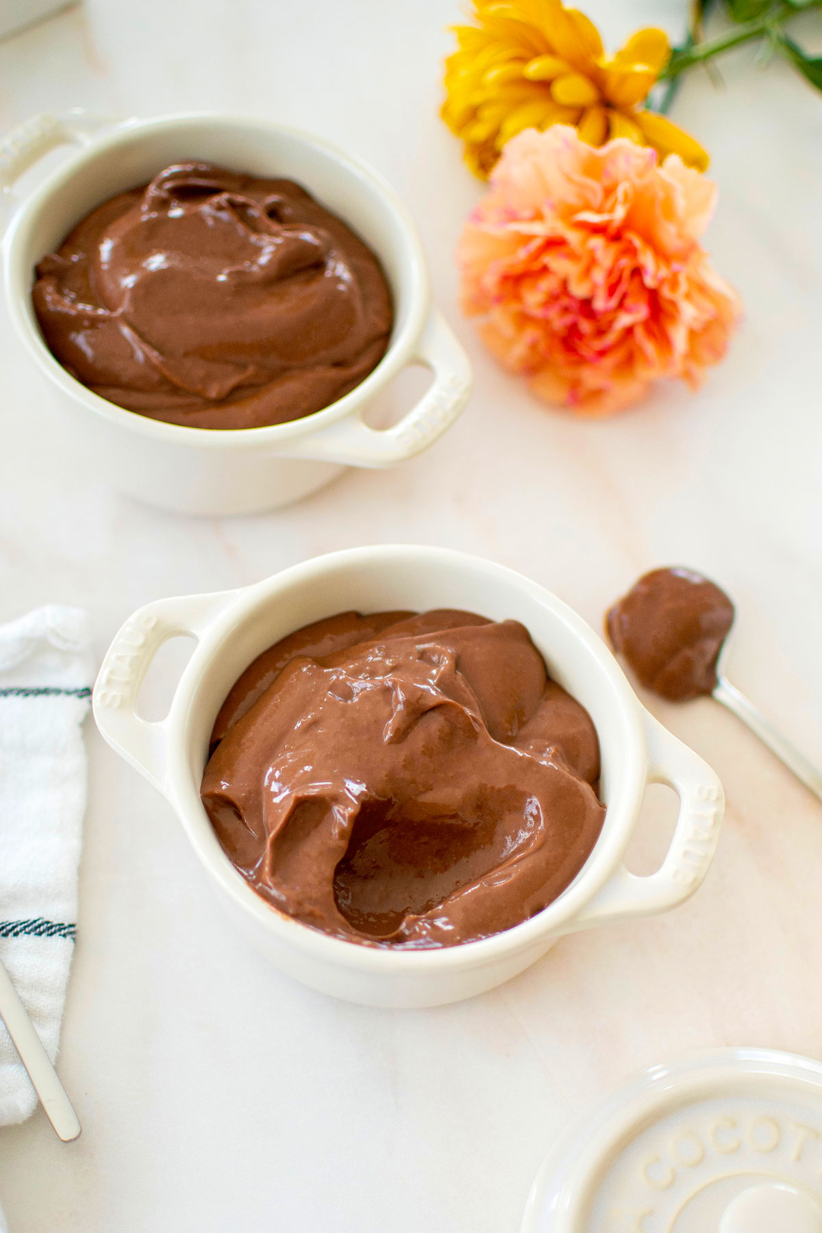 eggless chocolate peanut butter pudding in small ramekins on a marble counter with fresh flowers.