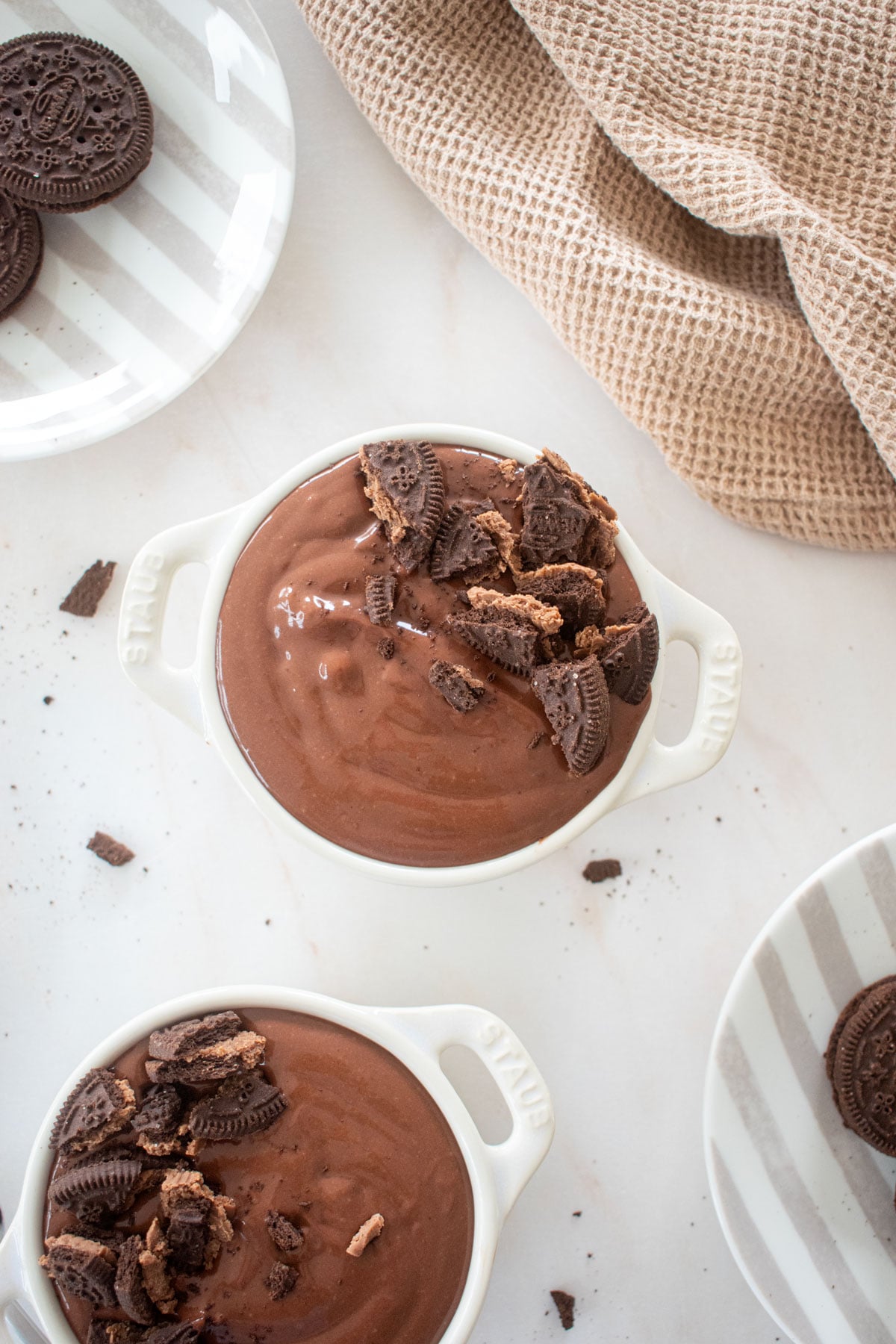eggless chocolate peanut butter pudding in small ramekins with crush chocolate cookies on top on a marble counter.