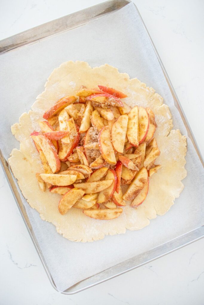 eggless honey apple galette dough with apple filling on a baking sheet on a white marble counter.