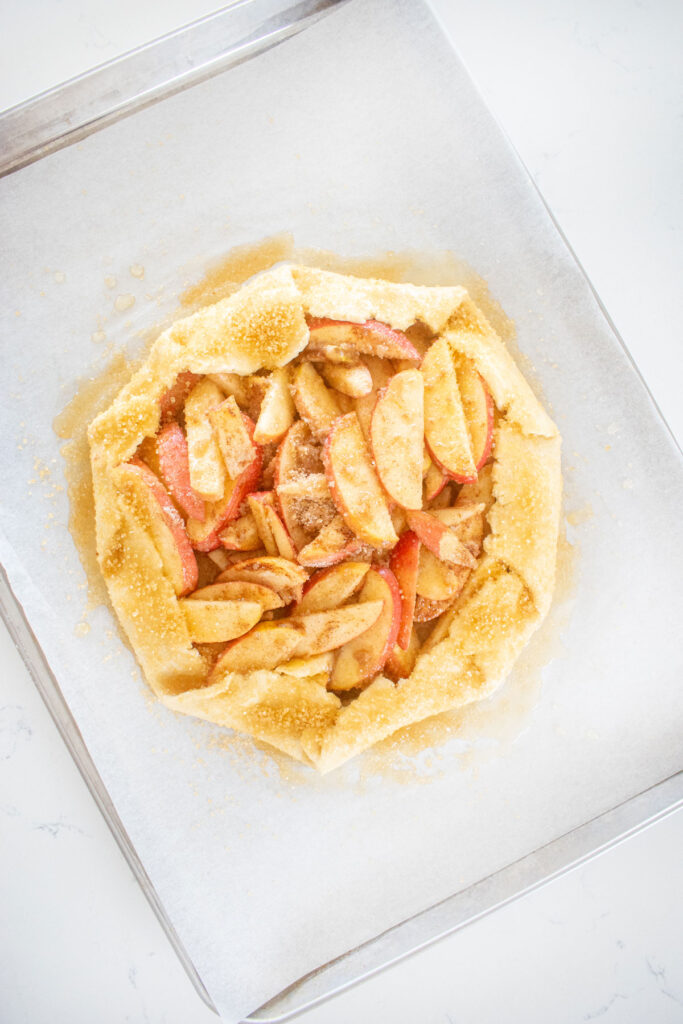 honey apple galette on a baking sheet with turbinado sugar.