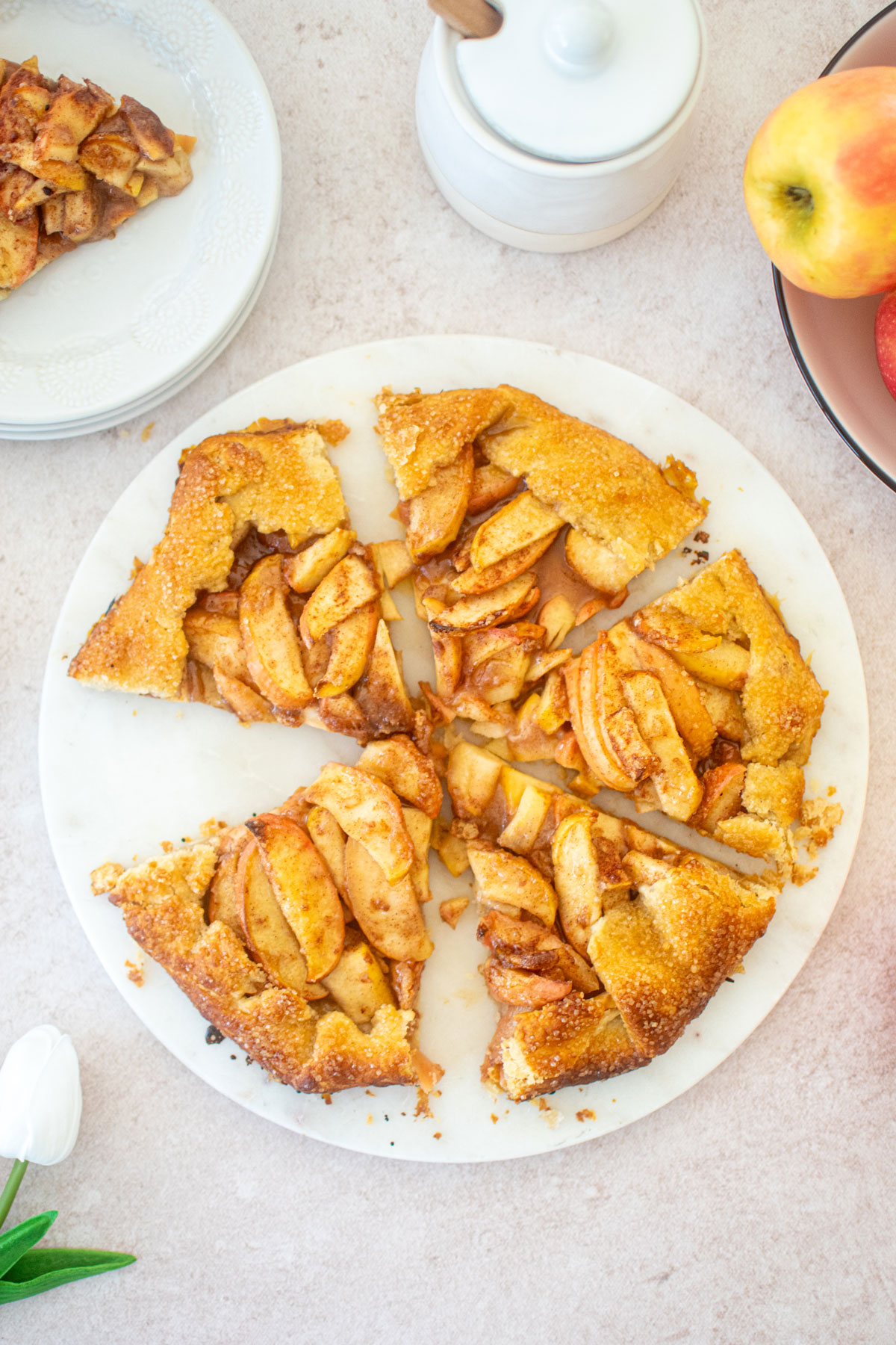 eggless honey apple galette cut into slices on a white marble serving board.