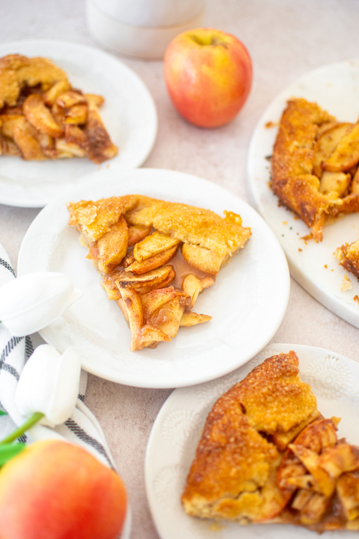 eggless honey apple galette slices. on white plates with fresh flowers and apples.