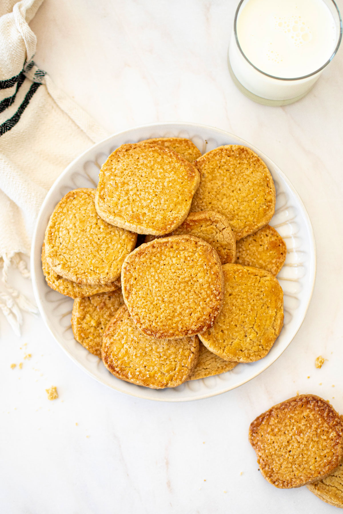 kamut flour shortbread cookies on a plate on a marble table with a glass of milk.