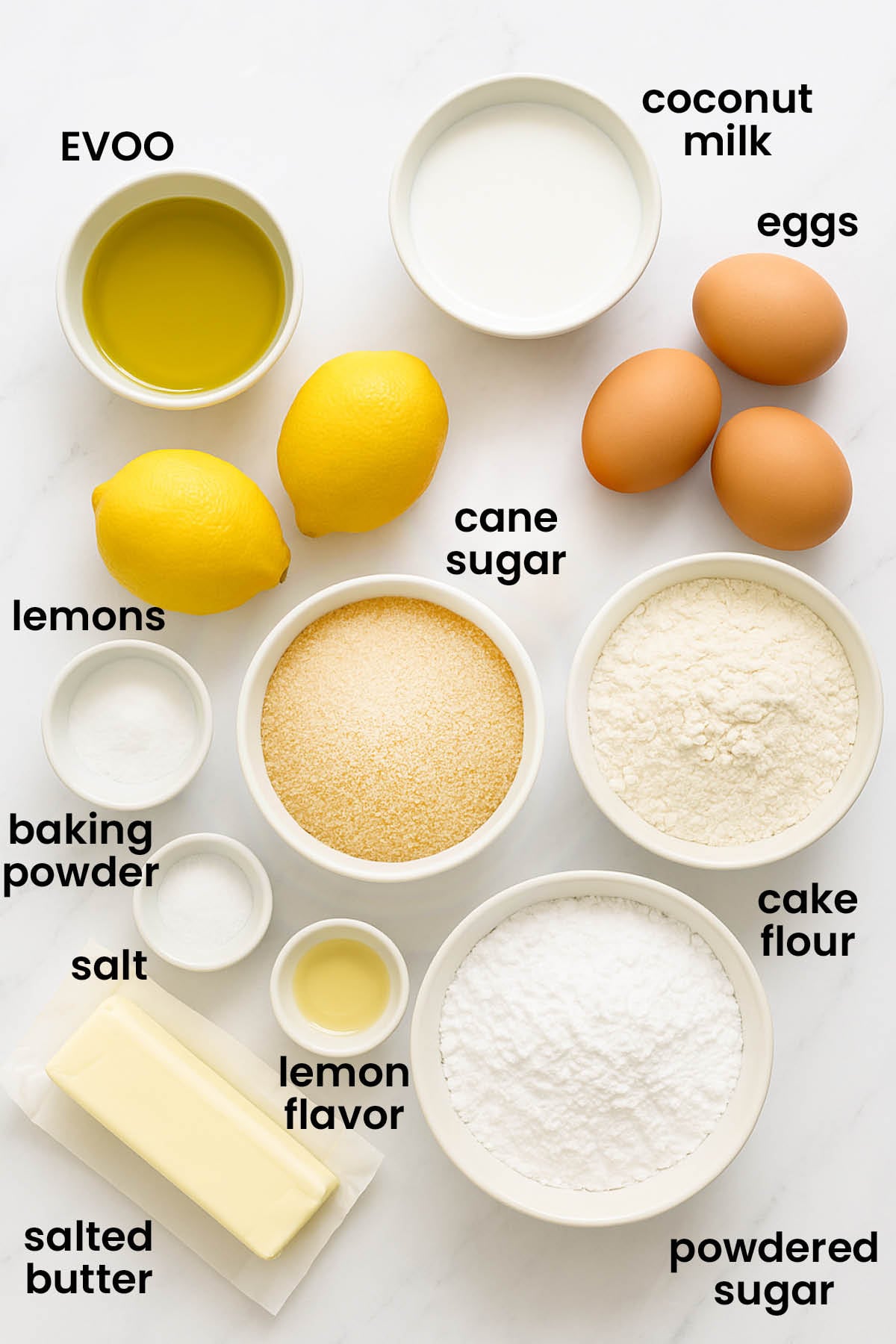 individual ingredients for lemon olive oil snack cake with lemon frosting on a white marble kitchen countertop.
