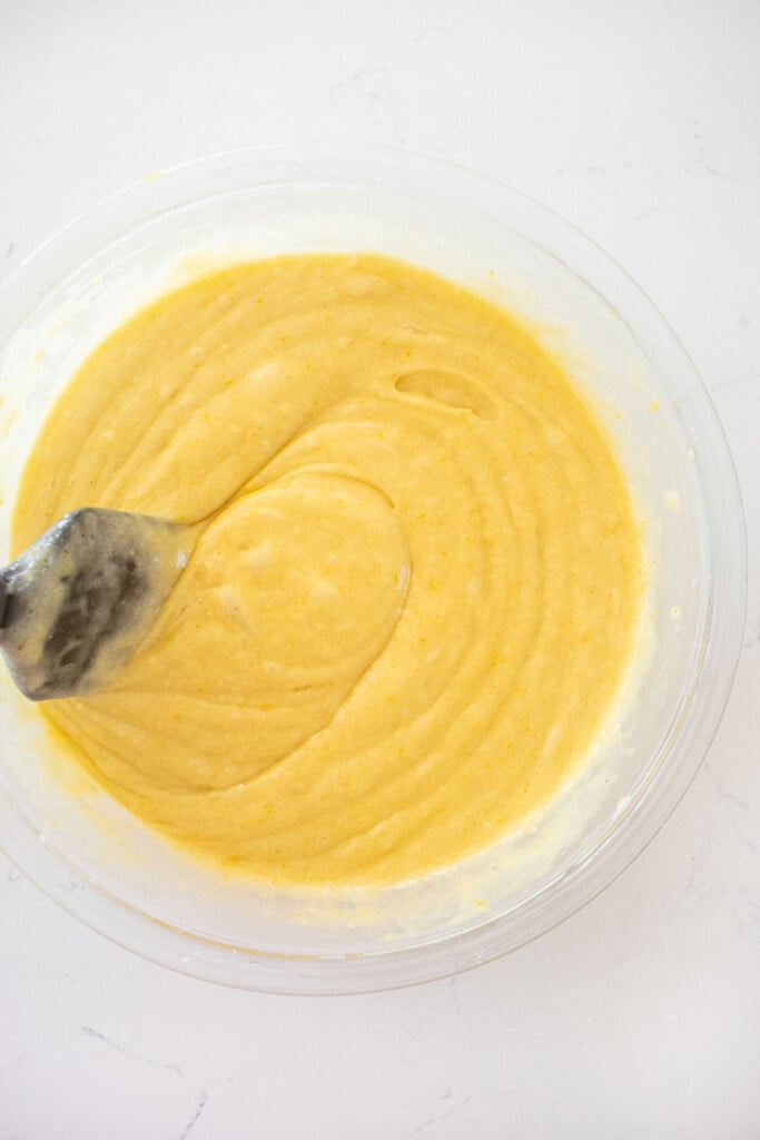 lemon olive oil cake batter in a glass mixing bowl on a white marble counter.