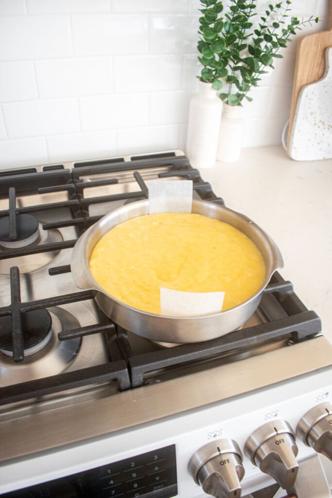 lemon olive oil snack cake batter in a cake pan sitting on top of a stove.