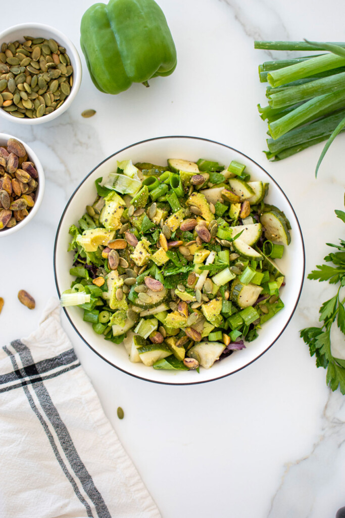 simple green salad in a large white bowl on a white marble countertop.