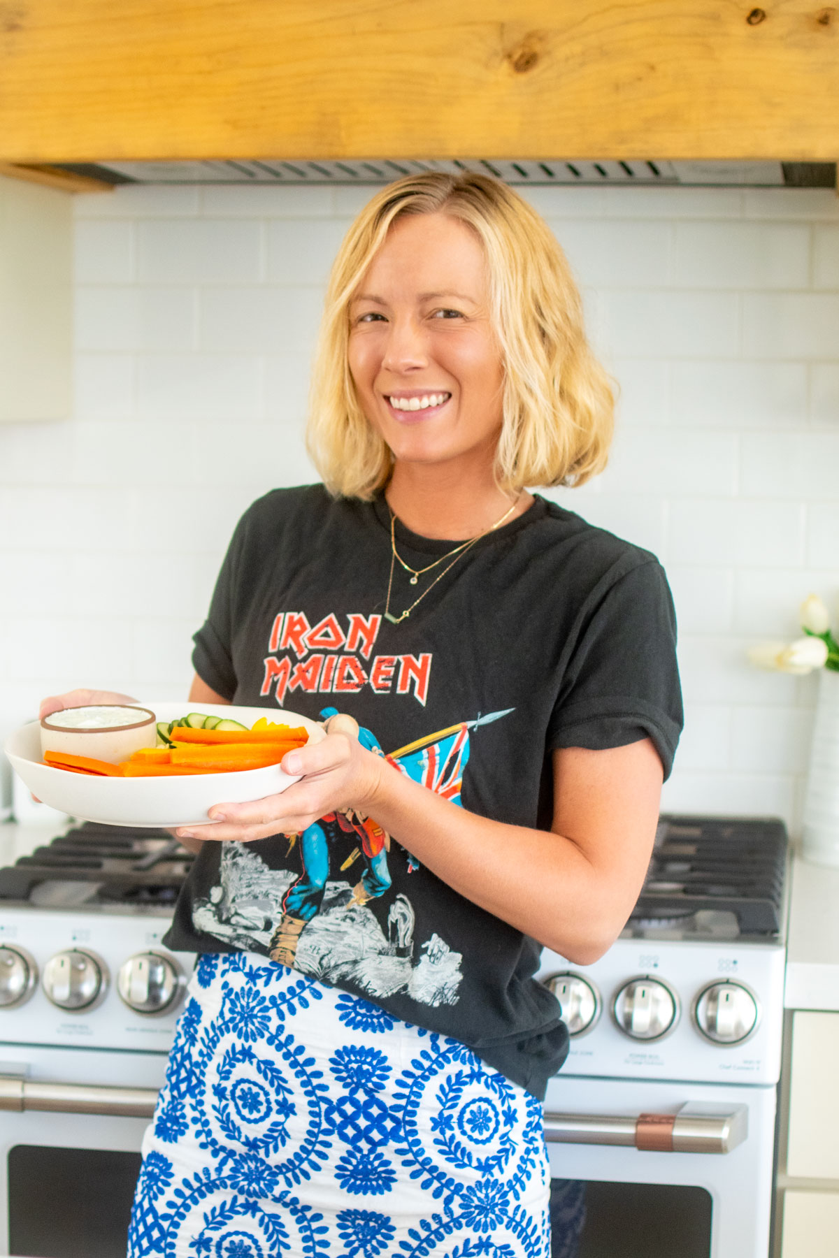 woman holding a veggie platter with organic tzatziki sauce in the kitchen.