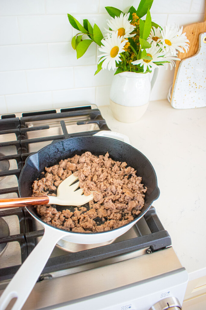 breakfast sausage being cooked in a cast iron skillet on the stovetop.