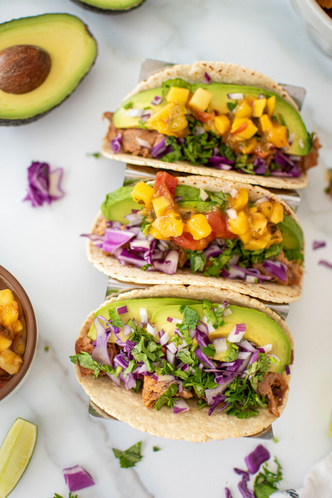 chili lime ahi fish tacos being assembled in a taco tray on a white marble countertop.