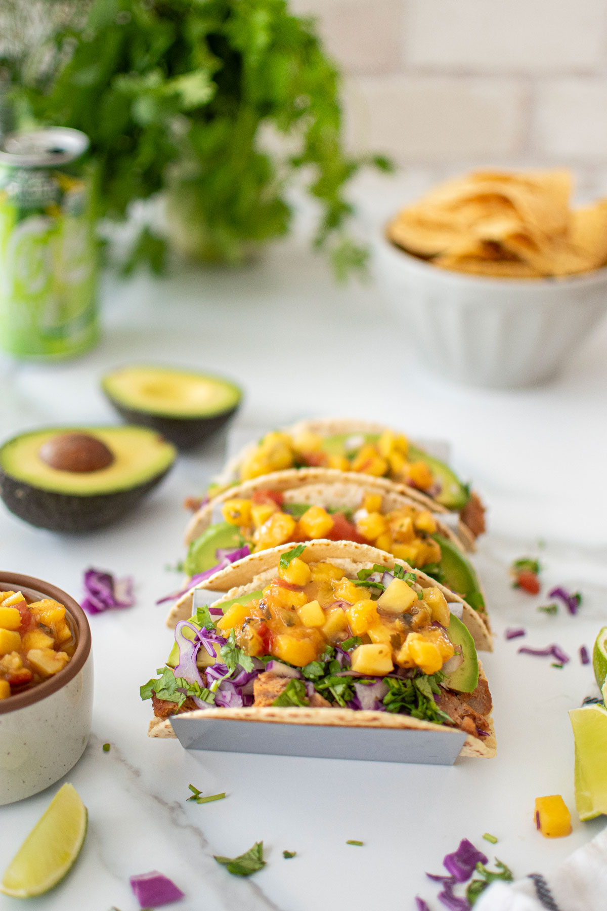 chili lime ahi fish tacos in a taco tray on a white marble countertop with a bowl of chips.