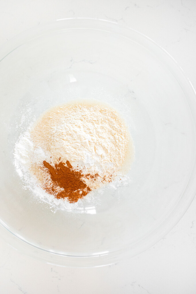 filling ingredients for sourdough peach galette in a glass mixing bowl on a white marble counter.