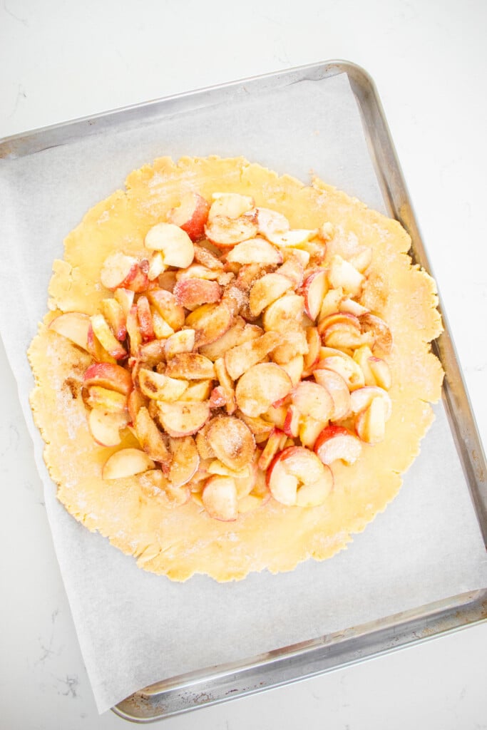 sourdough peach galette on a baking sheet ready to be folded.
