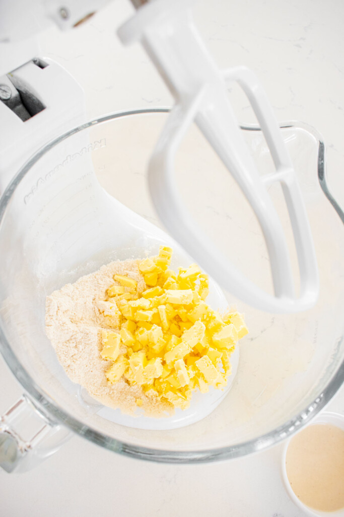 ingredients for sourdough pie crust in a glass mixing bowl on a white marble counter.