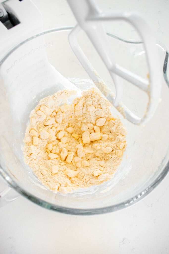 sourdough pie crust being mixed in a glass mixing bowl on a white marble counter.