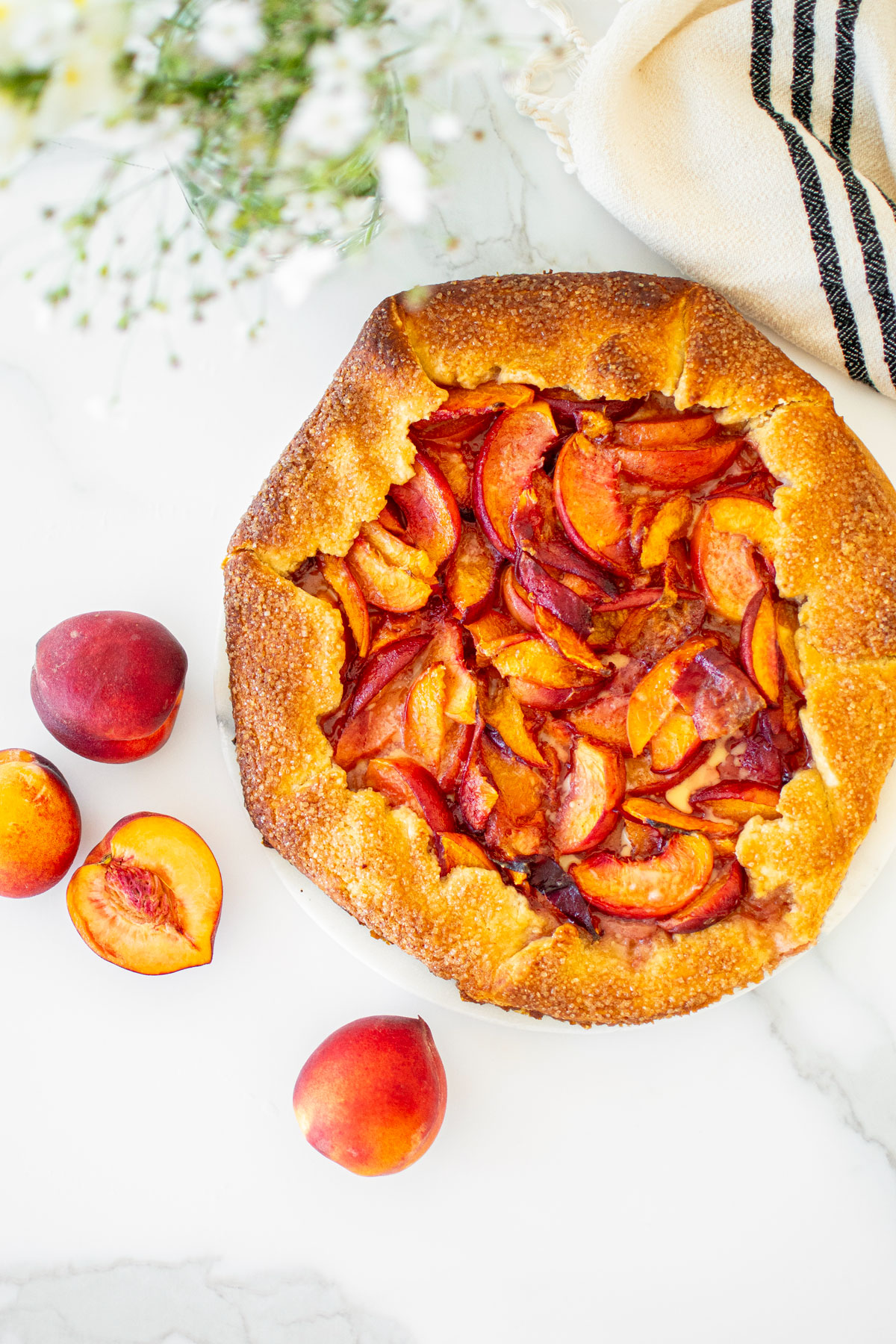 rustic sourdough peach galette on a marble serving board.