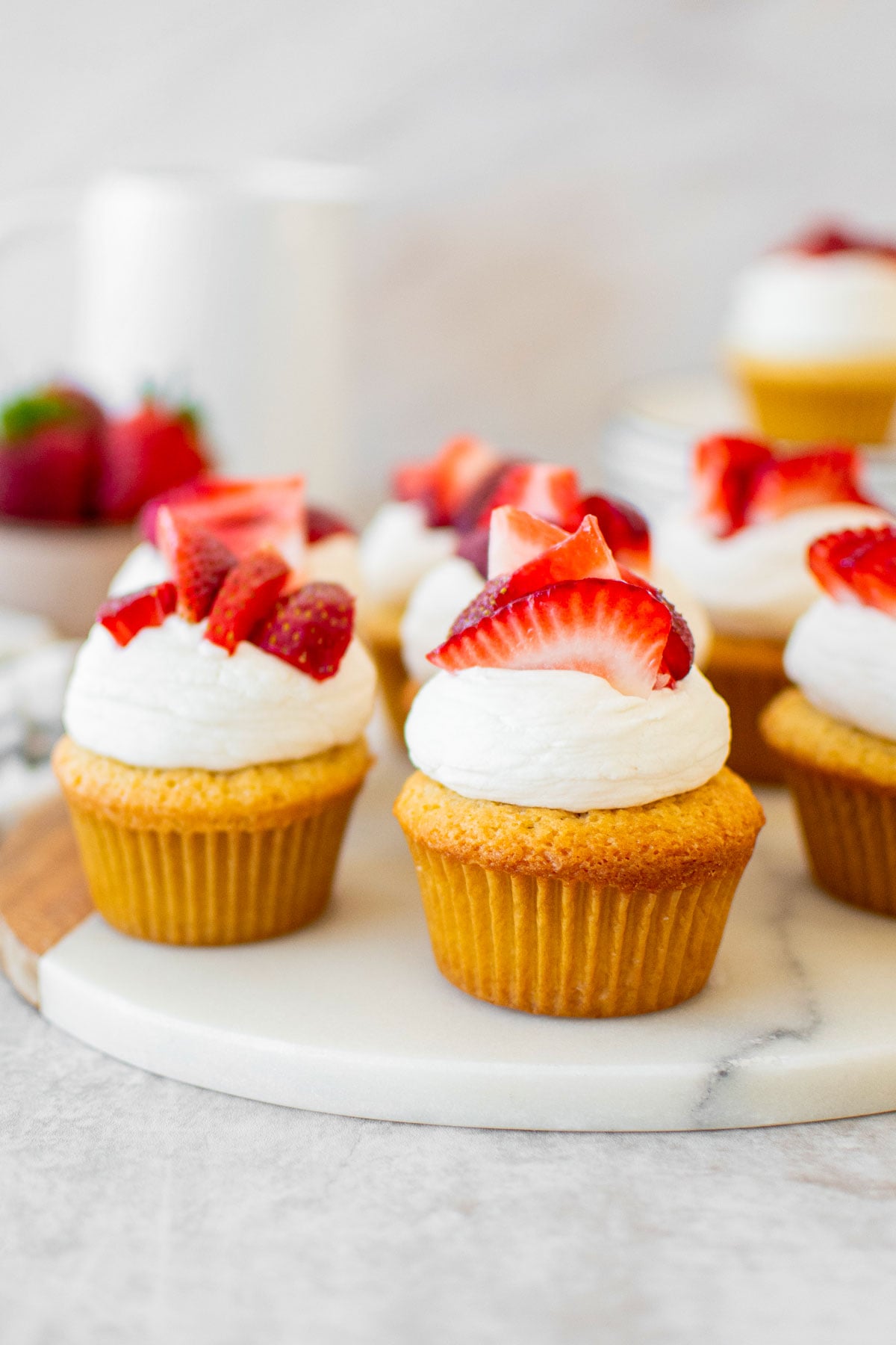 simple strawberry shortcake cupcakes on a marble serving board on a table.