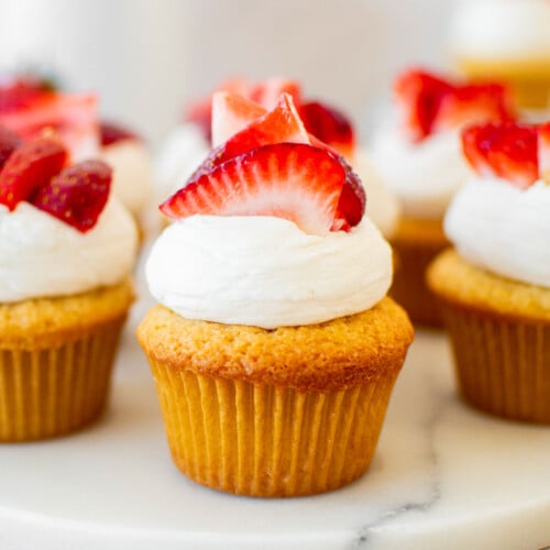 simple strawberry shortcake cupcakes on a marble serving board on a table.