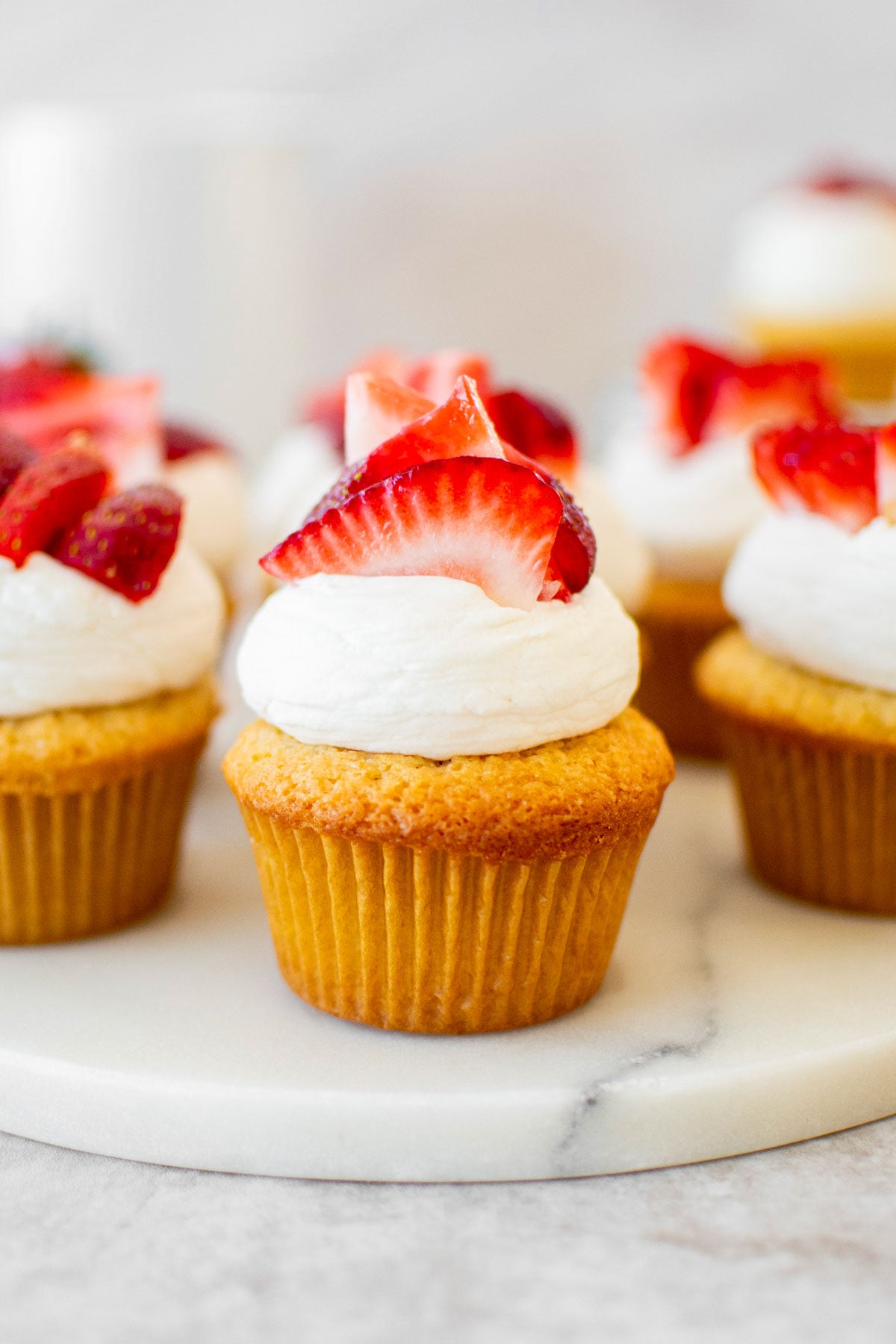 simple strawberry shortcake cupcakes on a marble serving board on a table.
