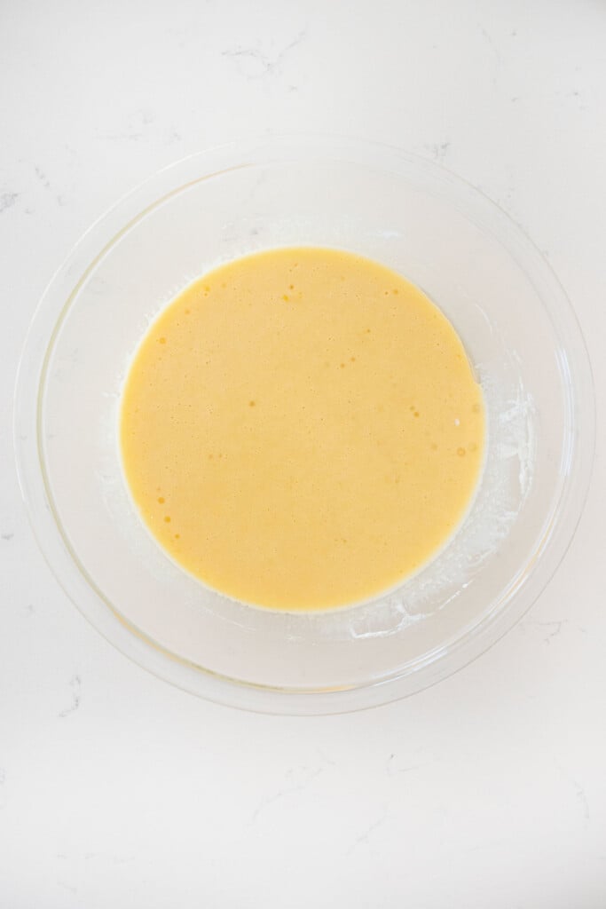 glass mixing bowl with wet ingredients for vanilla cake mixed together.