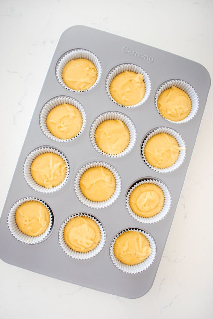 vanilla cupcake batter in a cupcake pan on a white marble counter.