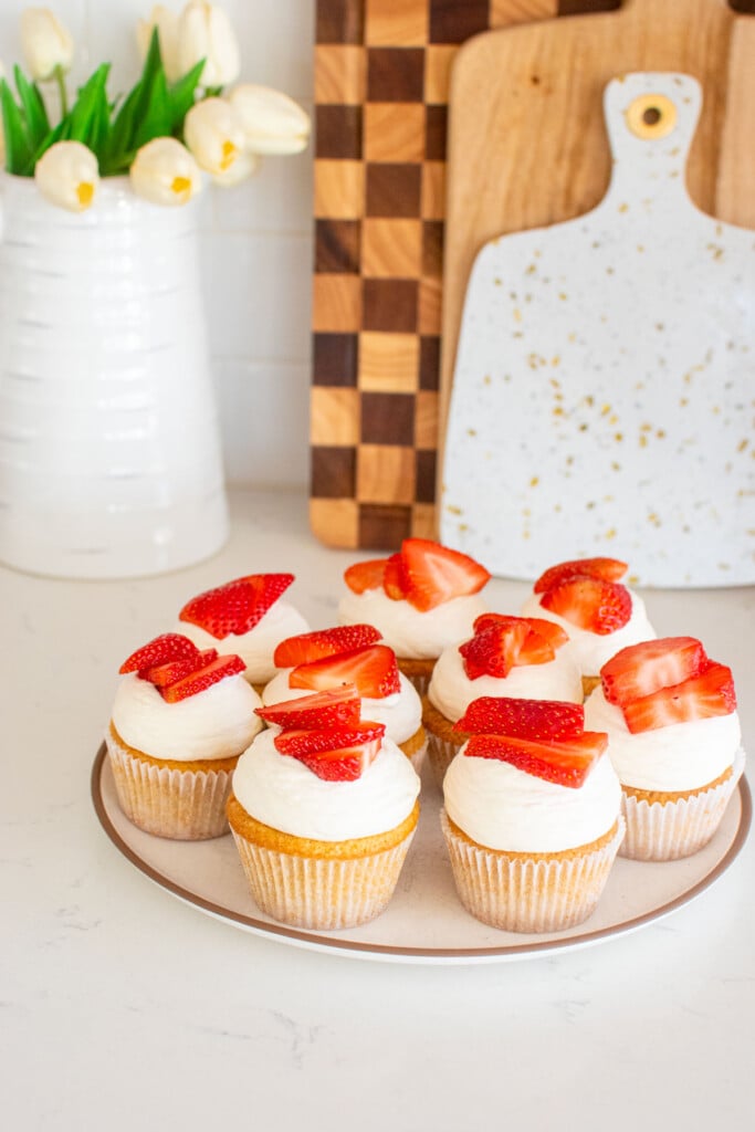 strawberry shortcake cupcakes on a plate on a white marble counter.
