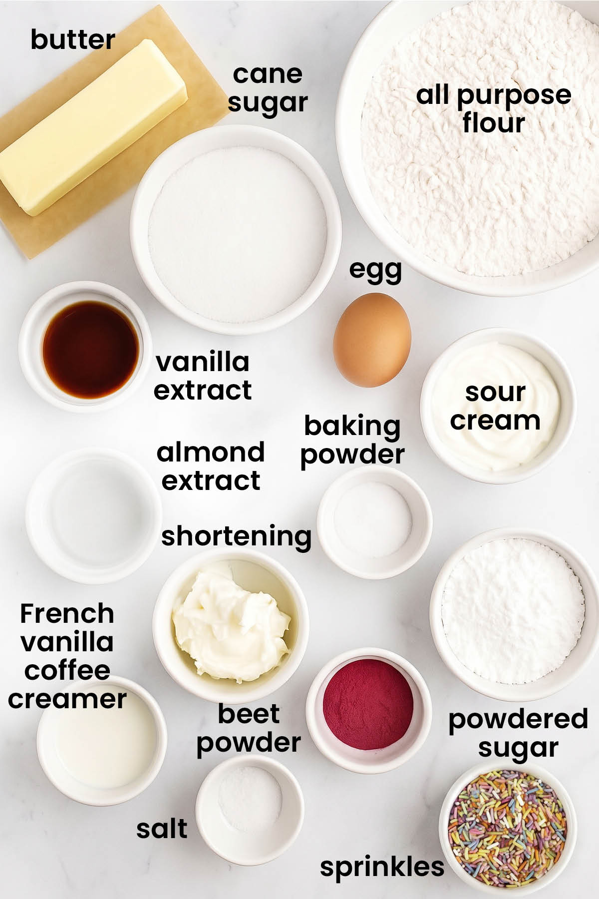 individual ingredients for soft sugar cookies with pink frosting laid out against a white background.