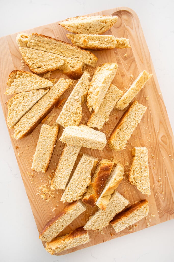 sourdough bread cut into thick sticks on a wood cutting board on a marble counter.