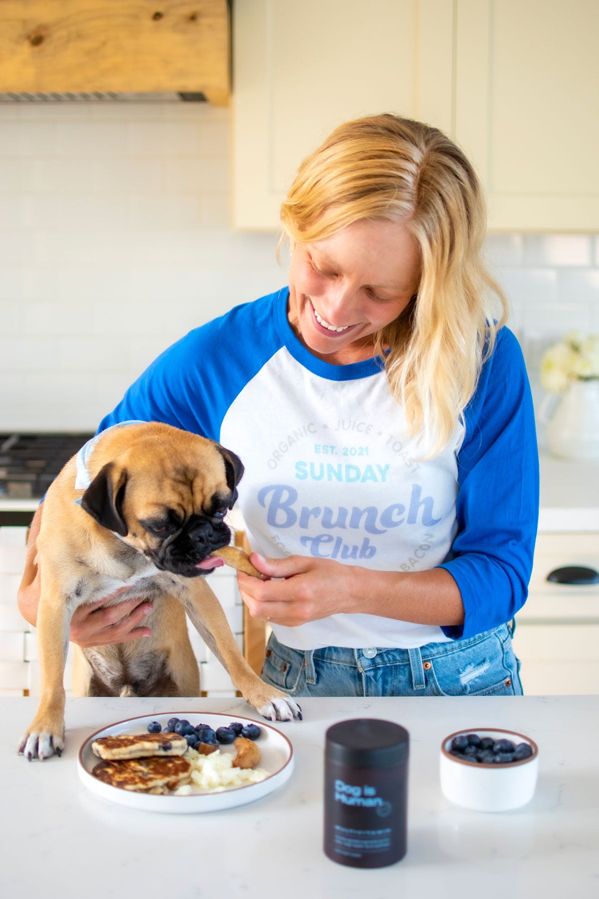 woman and pug in the kitchen eating sunday brunch for dogs.