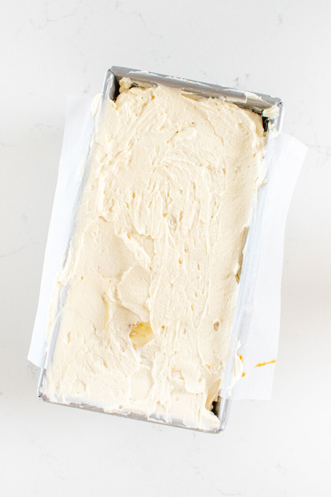 banoffee icebox cake being assembled in a loaf pan on a white marble counter.