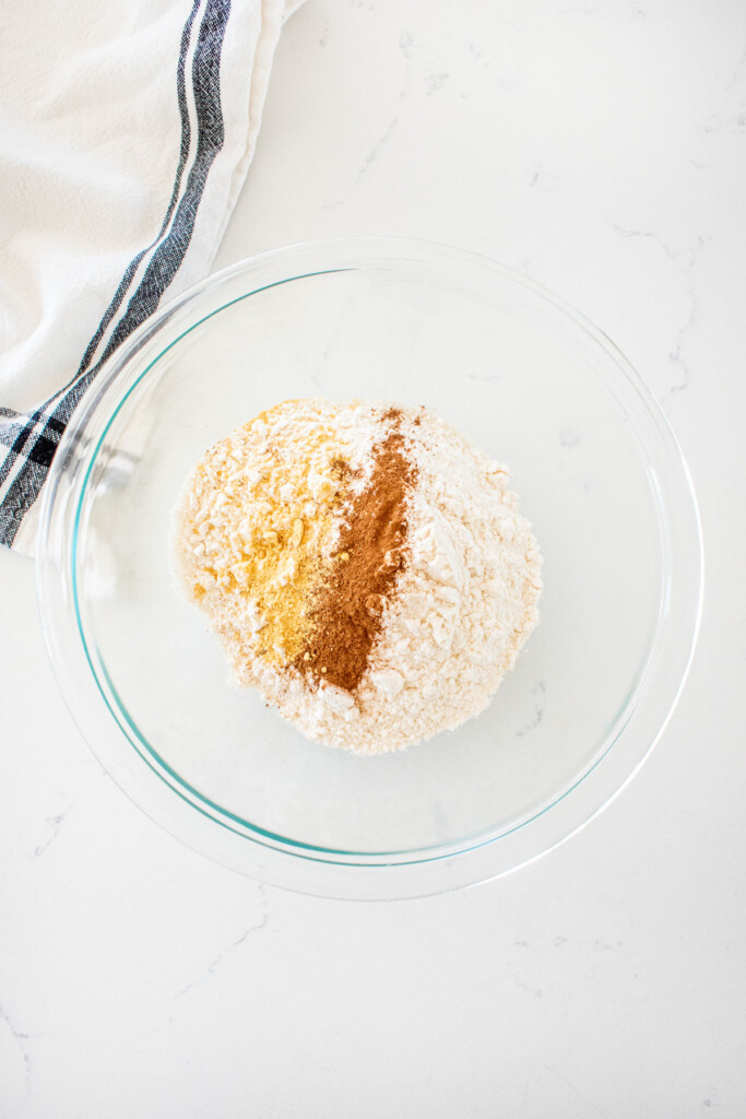 glass bowl with dry ingredients for blueberry honey crumble pie on a marble counter.