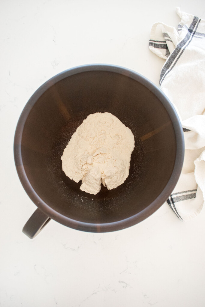 wood mixing bowl with flour and cane sugar on a marble counter.