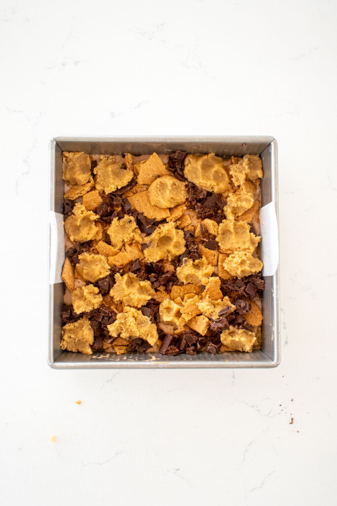 chocolate caramel smore bars in a square baking pan on a white marble counter.