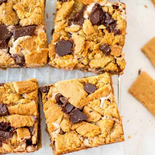 chocolate caramel smore bars cut into squares on a cooling rack on a white marble counter.