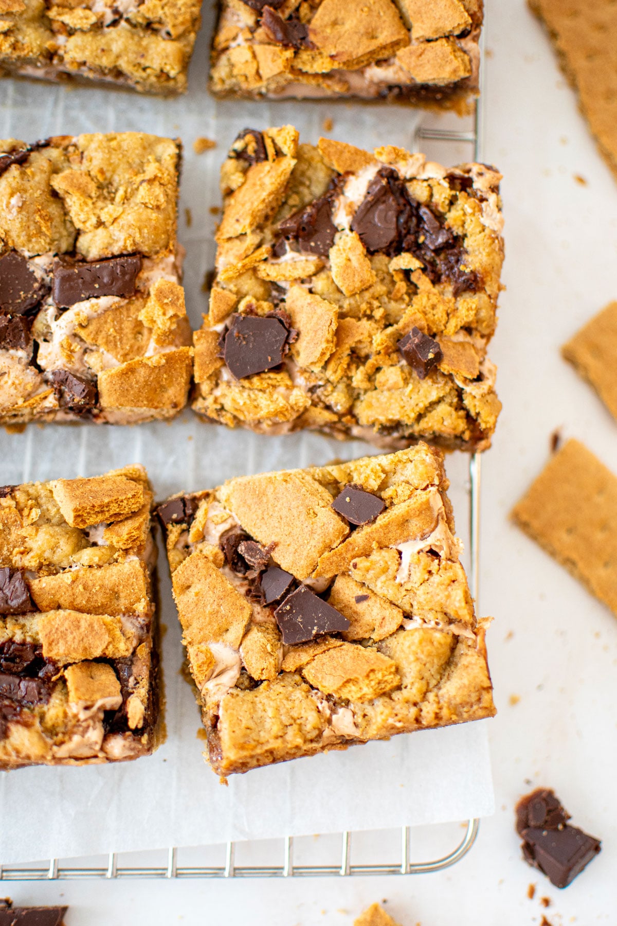 chocolate caramel smore bars cut into squares on a cooling rack on a white marble counter.