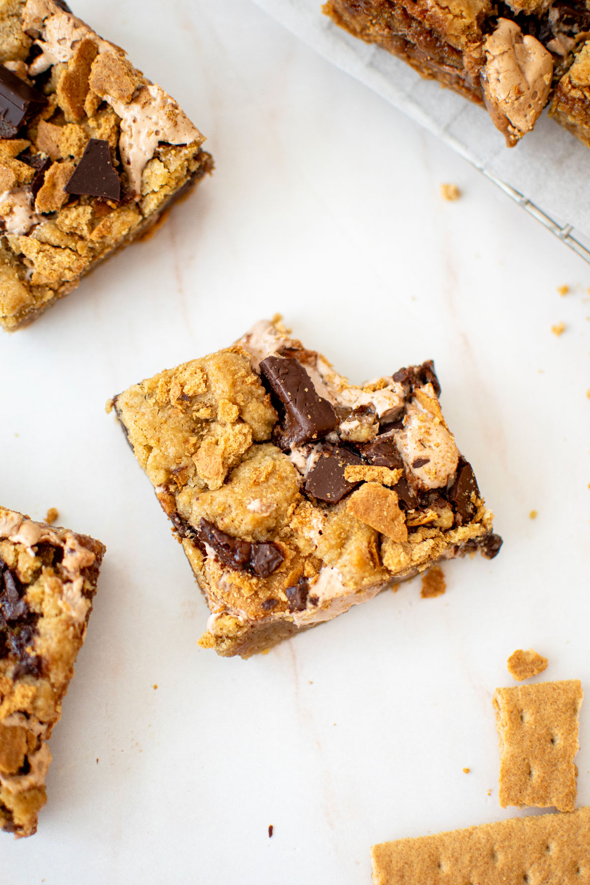 chocolate caramel smore bar with a bite taken out on a white marble counter.
