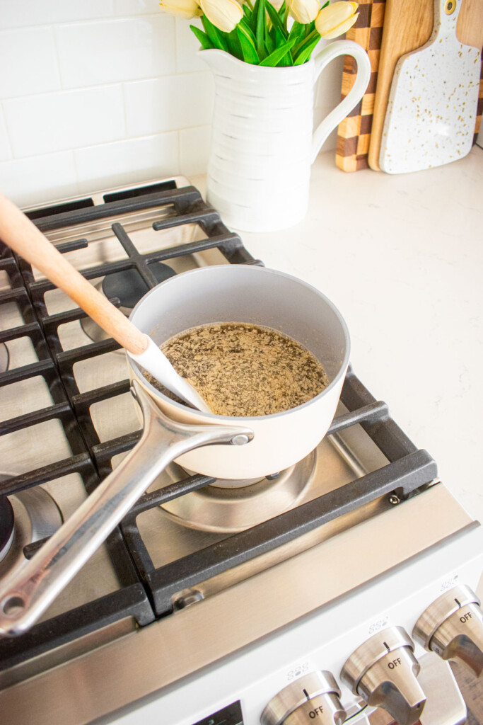 wet ingredients for honey almond coconut granola being cooked over the stovetop in a small pot.