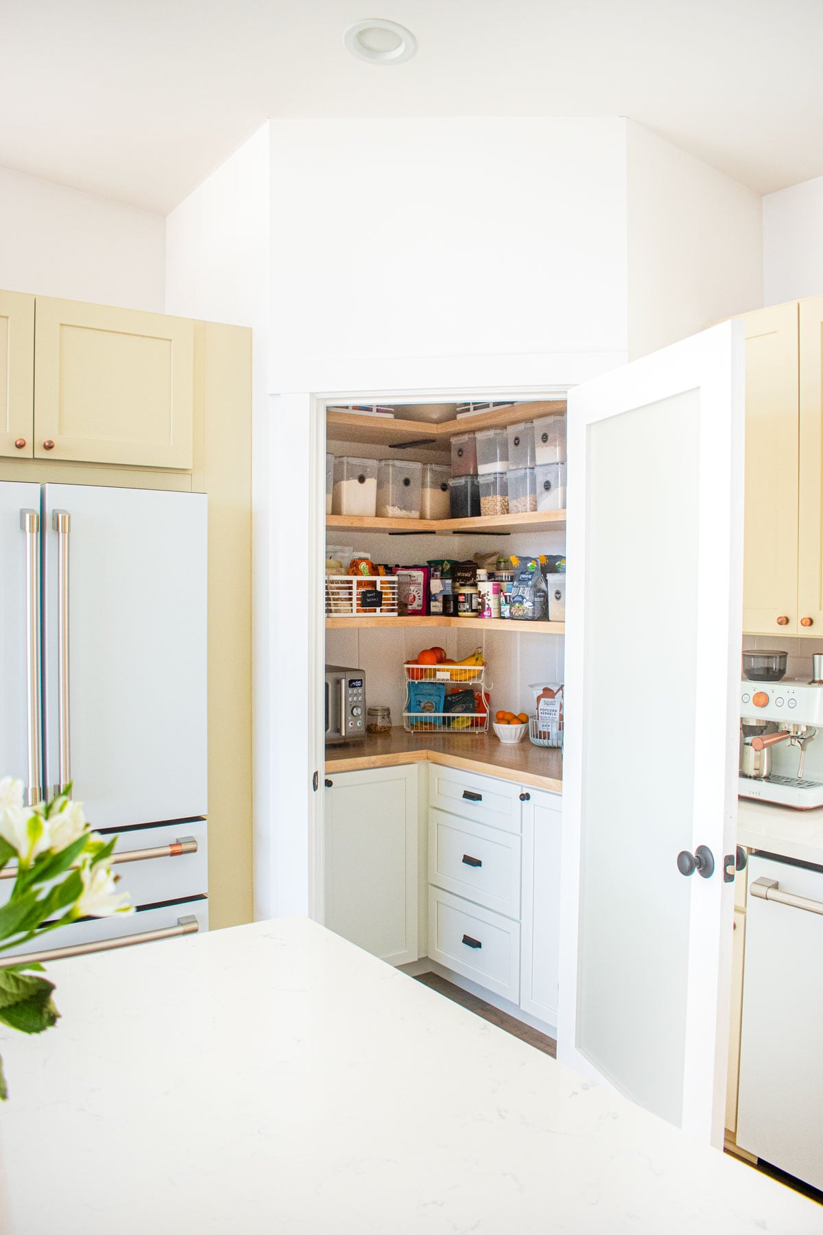 White and tan kitchen with pantry door opening to a diy kitchen corner pantry.
