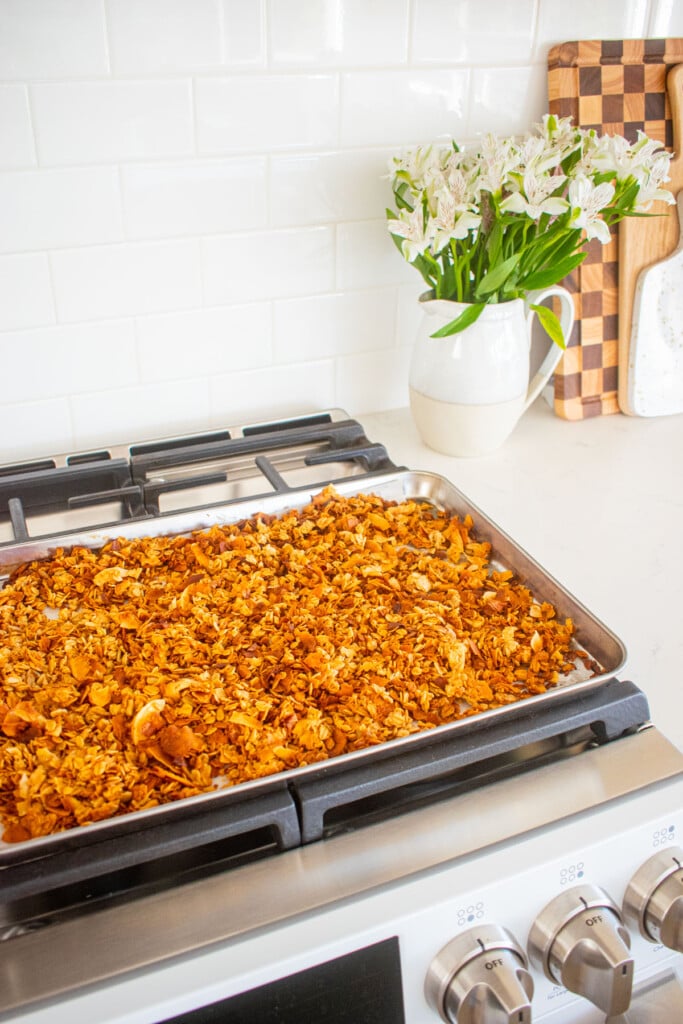 peanut butter honey granola for dogs on a baking sheet cooling on top of an oven.