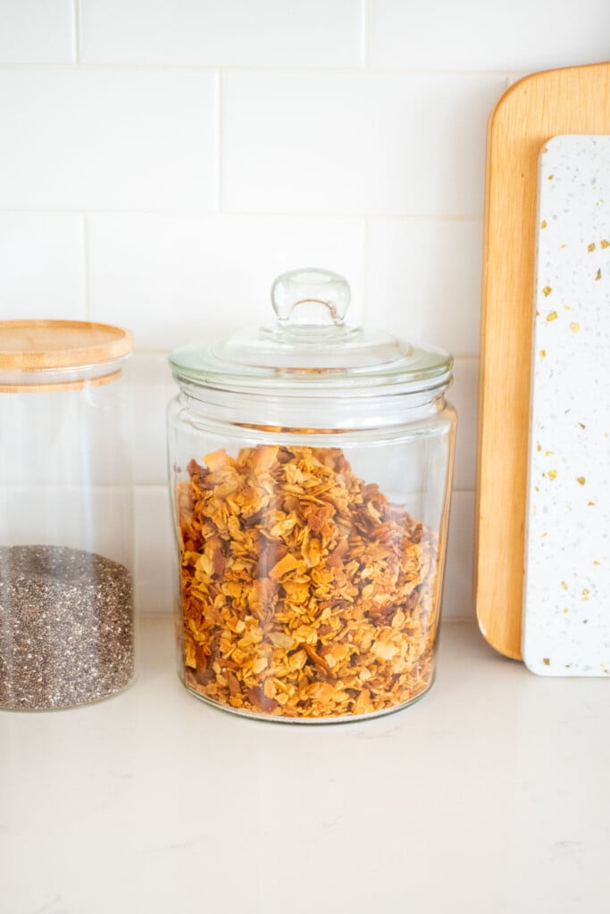 glass jar of granola on a white marble kitchen counter.