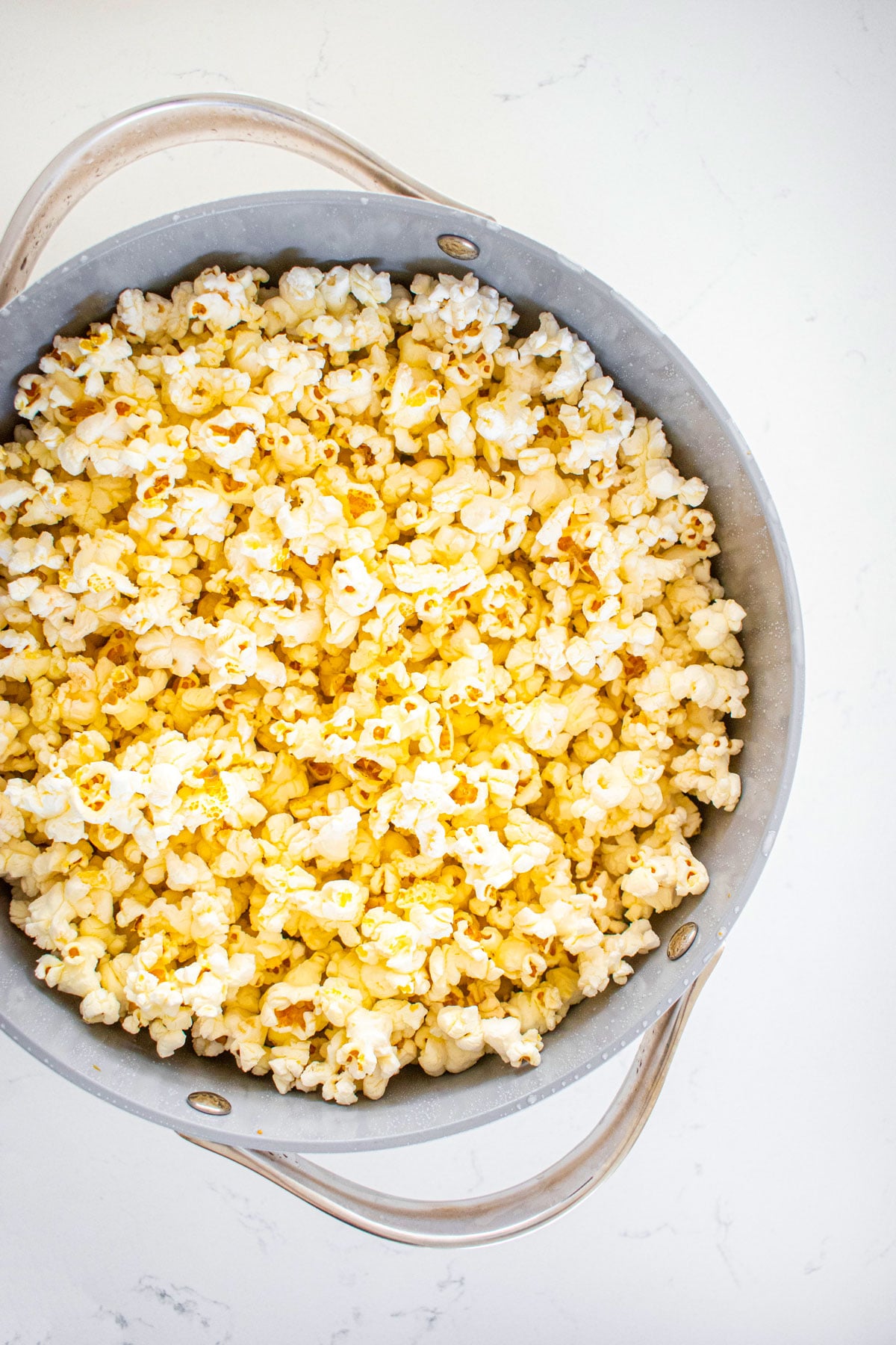 pink himalayan sea salt popcorn in a large stock pot on a white marble countertop.